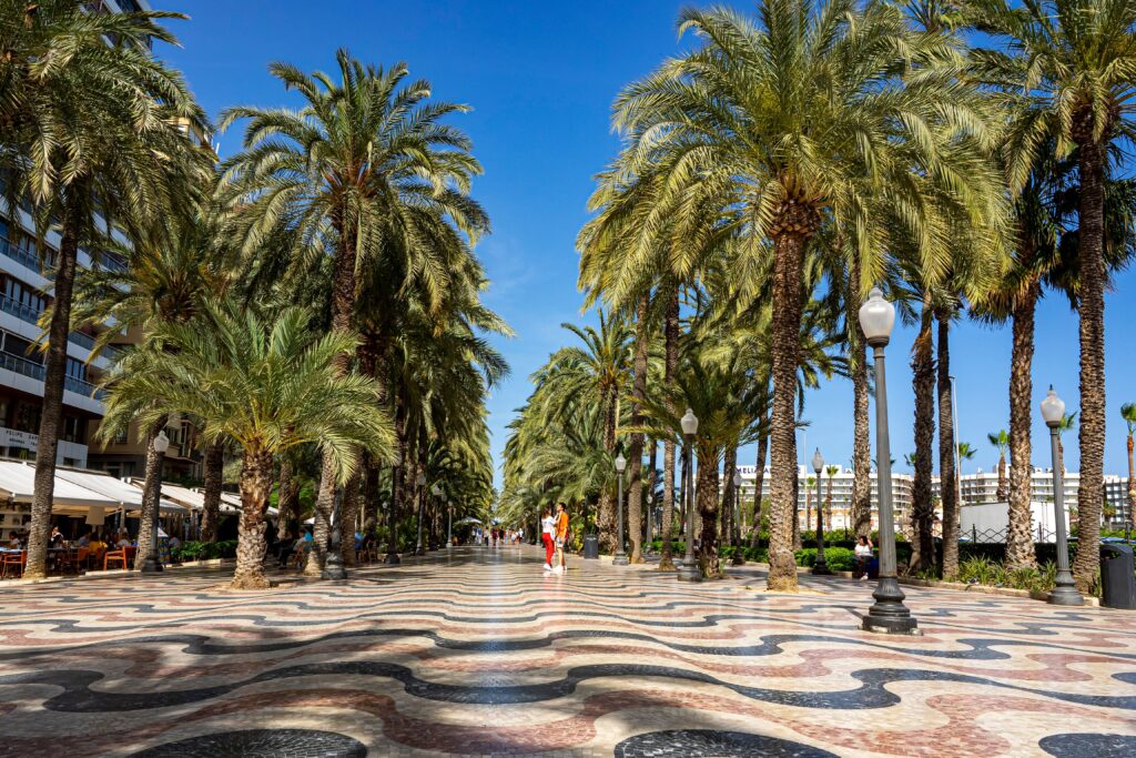 Explanada de España promenade in Alicante with palm trees and colourful wave-patterned pavement.